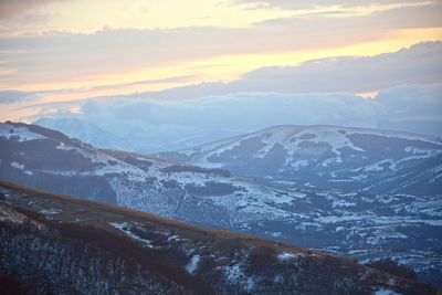 Aerial view of snowcapped mountains against sky during sunset