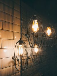 Illuminated light bulb against wall at night