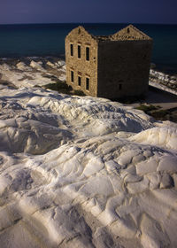 Built structure on beach by sea against sky