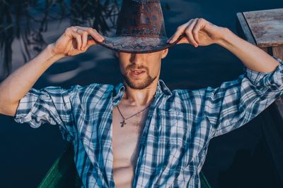 Midsection of man holding hat standing outdoors