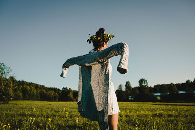 Rear view of a woman standing on a field against clear sky.