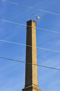 Low angle view of communications tower against blue sky