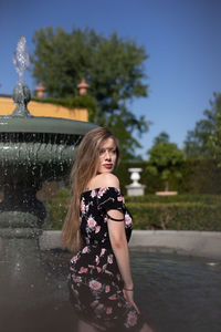 Portrait of young woman standing by fountain