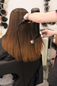 Cropped hands of hairdresser drying woman hair