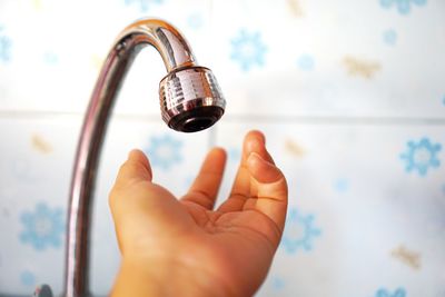 Cropped hand of woman under faucet