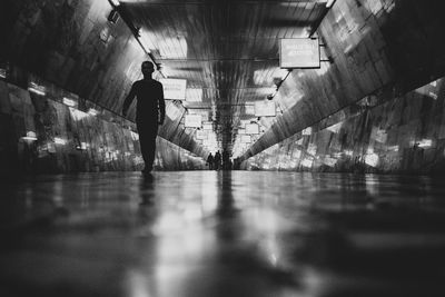 Rear view of man walking in illuminated tunnel