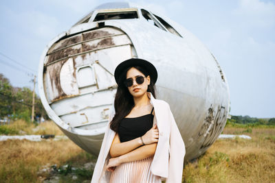 Portrait of woman wearing sunglasses standing on field against sky