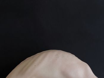 Close-up of shirtless man against black background