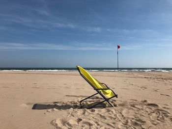 Deck chairs on beach against sky