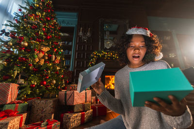 Portrait of young woman standing by christmas tree