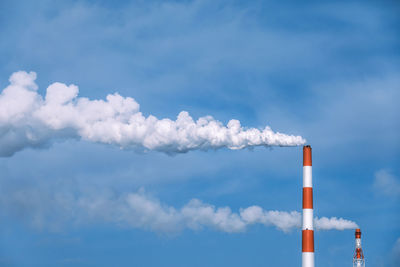 Low angle view of smoke emitting from chimney against sky