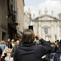 Rear view of people photographing in city