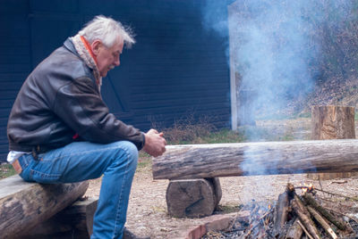 Midsection of man sitting on wood