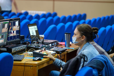 Young woman video editor in protective mask working on conference, seminar, use laptop editing video