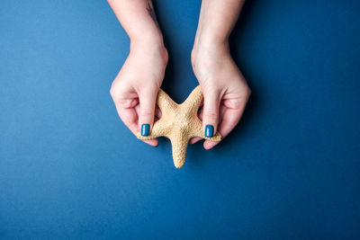 Stylish female manicure. starfish in female hands on blue background.