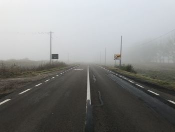 Empty road by fog against sky