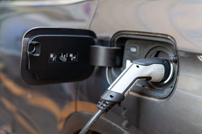 A cable is recharging an electric car at the charging station