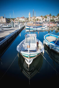 Sailboats moored at harbor against blue sky