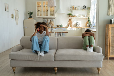 Young woman using digital tablet while sitting on sofa at home