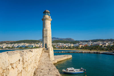 Lighthouse by sea against sky