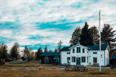 Houses and trees on field against sky