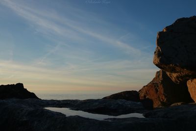 Rock formations in sea against sky during sunset