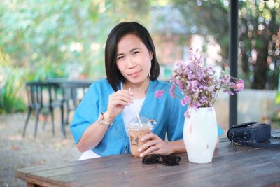 Portrait of a beautiful young woman drinking glass on table