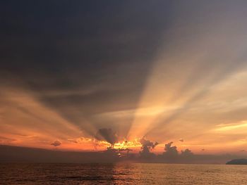 Scenic view of sea against dramatic sky during sunset