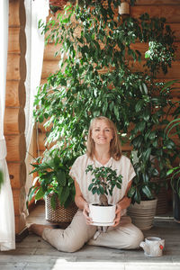 Portrait of young woman standing by christmas tree at home