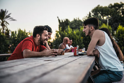Young men sitting on landscape against sky