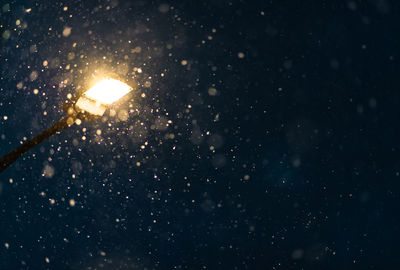 Illuminated street light against sky at night