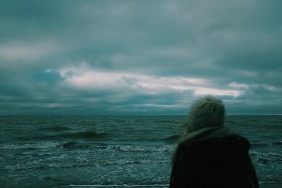 Rear view of woman looking at sea against cloudy sky