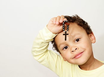 Portrait of cute boy holding camera over white background