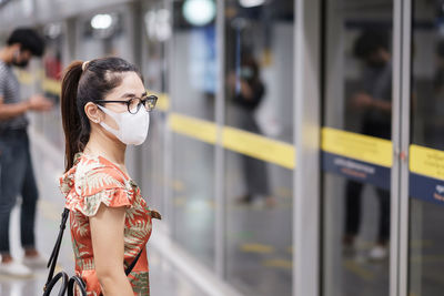 Woman looking at camera while standing against train