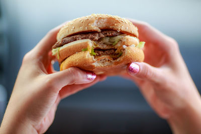 Close-up of hands holding hamburger outdoors