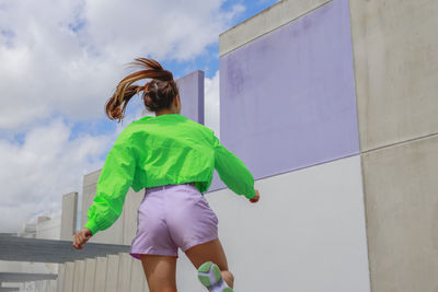 Young woman enjoying while dancing in front of wall