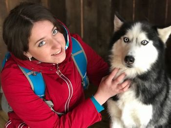 Portrait of smiling young woman with siberian husky at home