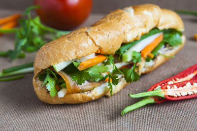 Close-up of sandwich with tomato and chili peppers on table