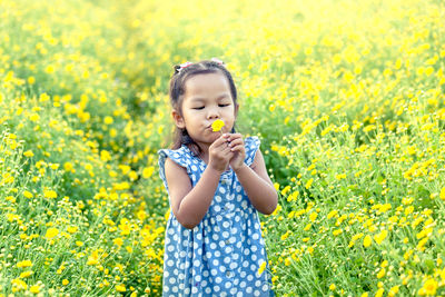 Carefree girl playing with flower on field