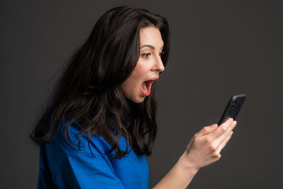 Young woman using mobile phone against black background