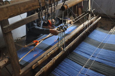 Midsection of person weaving loom