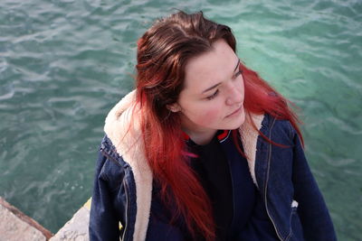 Beautiful young woman looking away while standing by sea