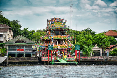 Traditional building by lake against sky