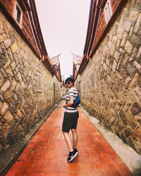 Full length portrait of woman standing on wall