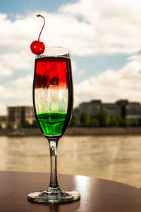 Close-up of colorful wineglass on table against sea