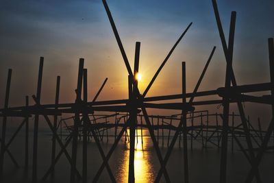 Silhouette cranes against sky during sunset