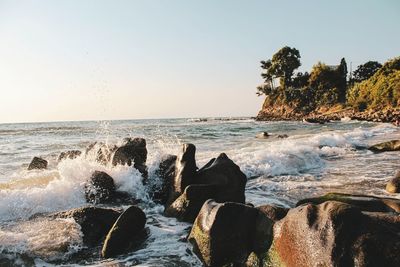 Rocks in sea against clear sky