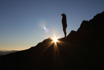 Silhouette man standing on mountain against sky during sunset