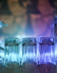 Close-up of wineglasses arranged on illuminated shelf in bar