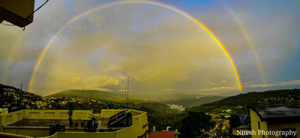 Rainbow over buildings in city against sky